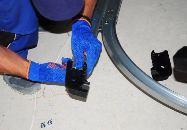 Close-up of a bent garage door track being straightened during track repair and alignment.