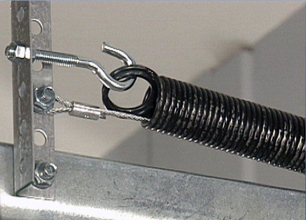 Close-up of a garage door extension spring being adjusted for correct tension.