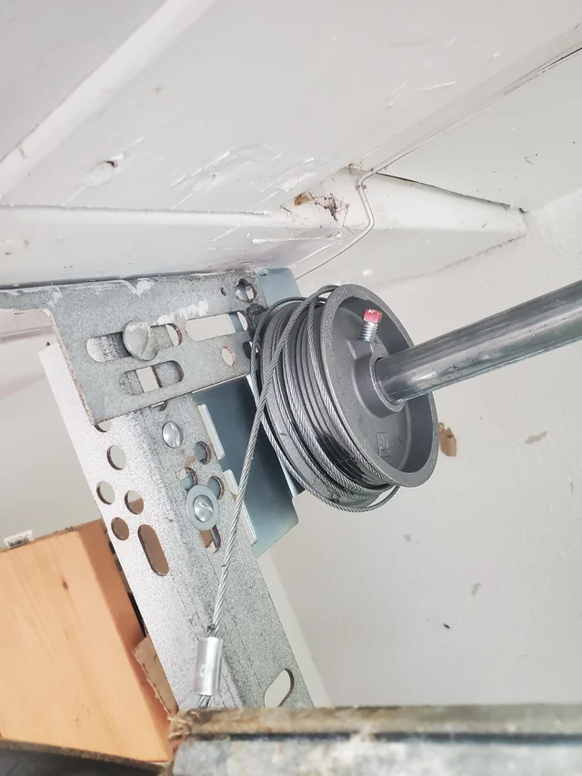 Hands adjusting a garage door cable during a cable replacement service.