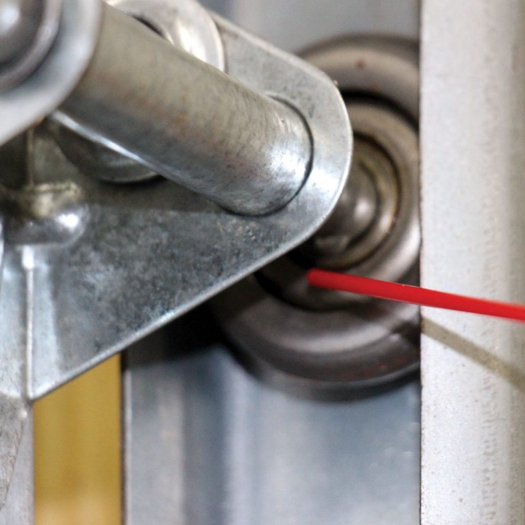 Technician using specialized lubricant on garage door springs for longevity.