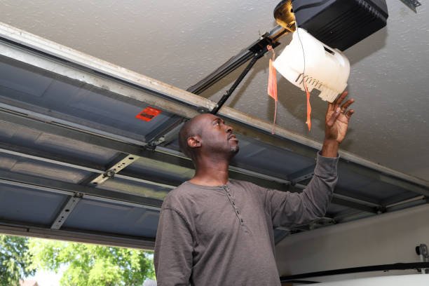 Hands installing the motor unit of a garage door opener during installation service.