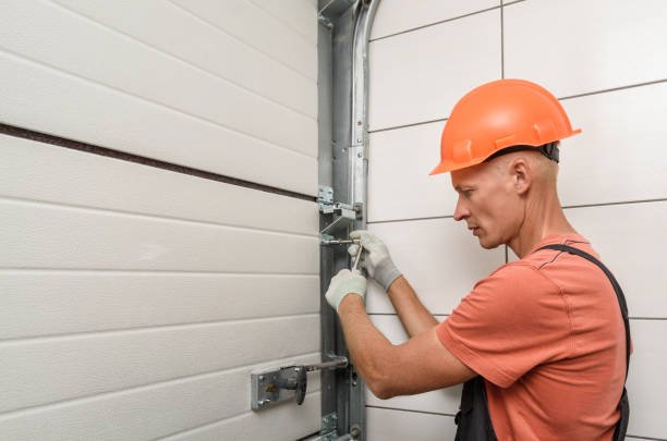 Hands lubricating moving parts of a garage door during a repair service.