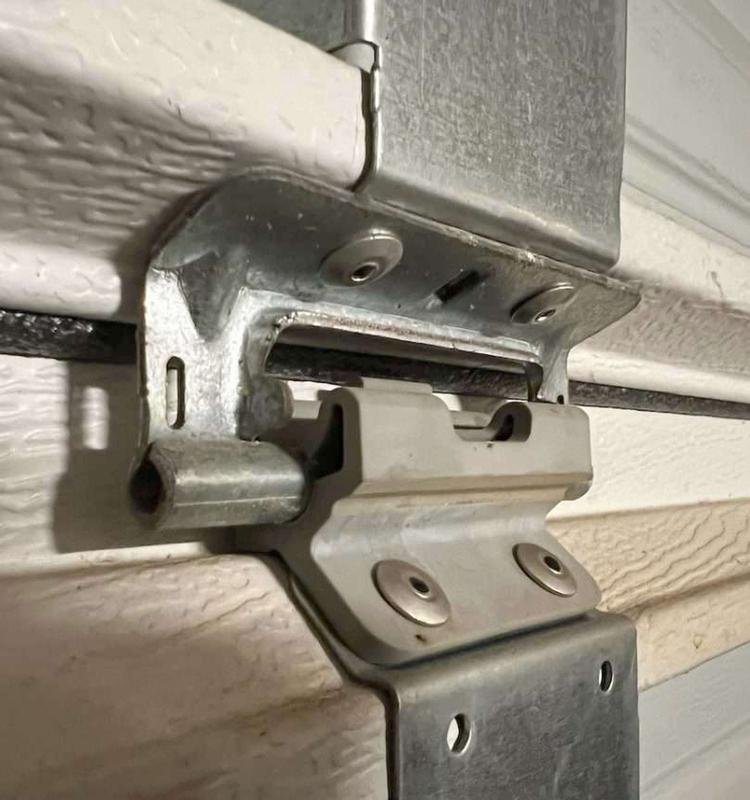 Close-up of a garage door hinge being replaced with a durable, high-quality part.